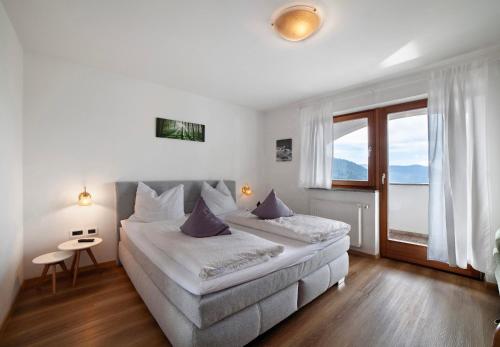 a bedroom with two beds and a large window at Hotel Klausthaler in Meltina