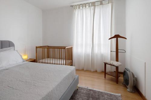 a bedroom with a bed and a crib and a window at São Roque Apartment in São Roque