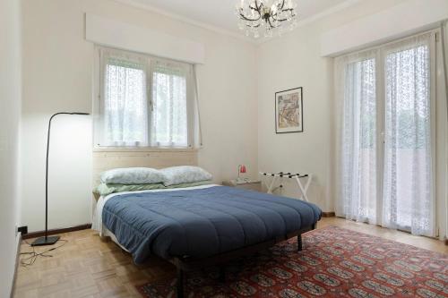 a bedroom with a bed and a chandelier and windows at Appartamento Marconi 35 Pergine in Pergine Valsugana