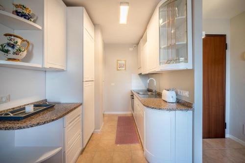 a kitchen with white cabinets and granite counter tops at La terrazza sul faro in Lignano Sabbiadoro