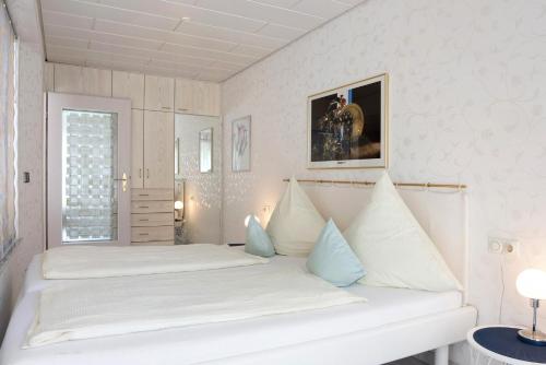 a white bedroom with two beds and a window at Ferienwohnung am Schlosssee in Salem