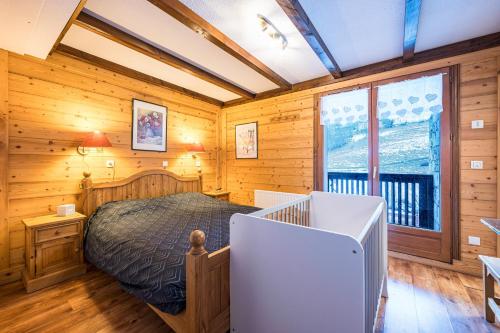 a bedroom with a bed in a room with wooden walls at Appartement Génépi dans Chalet 14p in Praranger
