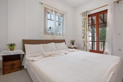 a white bed in a bedroom with a window at Areti Orfeas Apartment 5 in Vasilikos