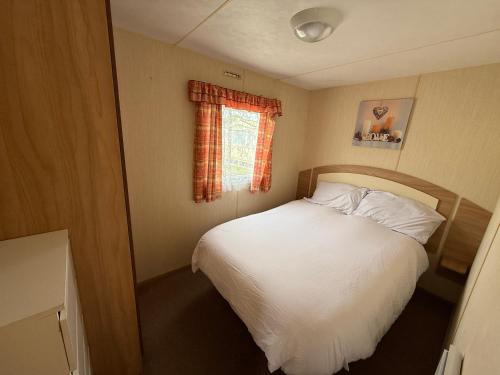 a small bedroom with a bed and a window at Sunnymede G20 with Hot Tub - pet friendly, Wifi, bed linen - Meadow Lakes Caravan & Lodge Hire in Ingoldmells