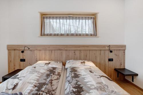 a bed with a wooden headboard and a window at Chalet Kb in Livigno