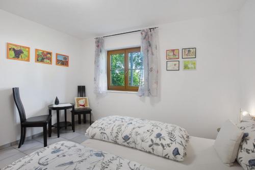 a white bedroom with a bed and a window at Unterm Nussbäumle in Adelhausen