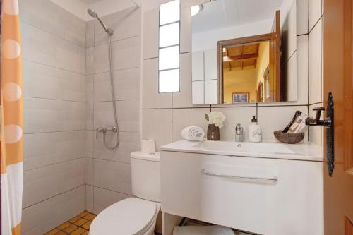 a bathroom with a toilet and a sink and a mirror at Casa Candelaria in Arico