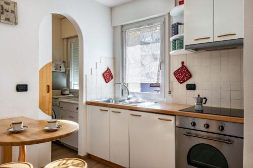a kitchen with white cabinets and a sink and a table at Casa Mara in Predazzo