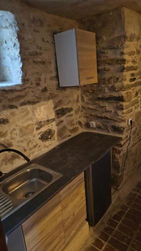a kitchen with a sink and a stone wall at Pyrgos Mitsakou 2 in Vathia