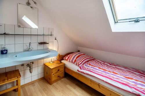 a small bedroom with a bed and a sink at Nordsee Ferienwohnung Möwe in Thunum