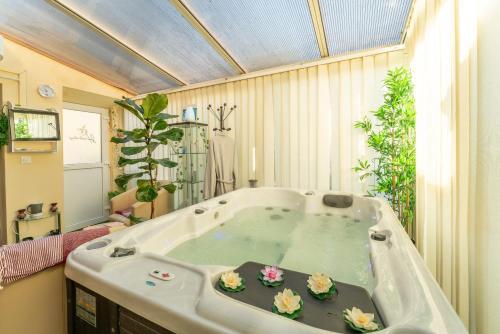 a large bathroom with a tub with flowers in it at Le Chalet Houda et spa en option in Nîmes