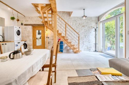 a kitchen and living room with a wooden staircase at Logement Le Buffet De La Gare in Falgueyrat