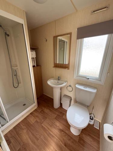 a bathroom with a toilet and a sink and a shower at Sunnymede G20 with Hot Tub - pet friendly, Wifi, bed linen - Meadow Lakes Caravan & Lodge Hire in Ingoldmells