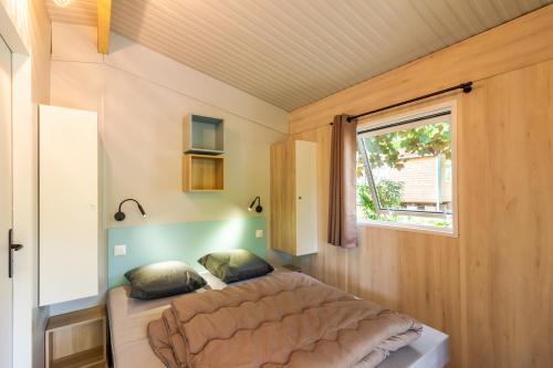 a bed in a small room with a window at Chalet Franklin 2 personnes in Saint-Martial-de-Nabirat