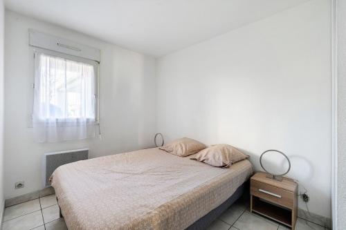 a white bedroom with a bed and a window at Appartement Du Golf - Pornic 1 in Pornic
