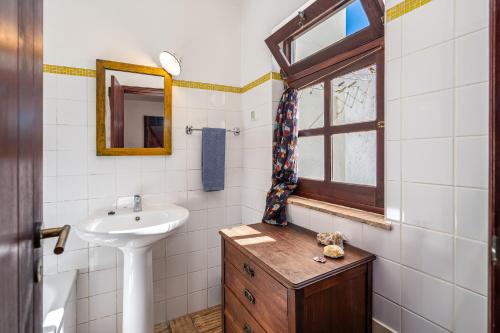a white bathroom with a sink and a window at Casa da Praia 1 in Budens