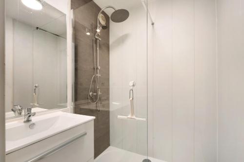 a white bathroom with a shower and a sink at Appartement Du Golf - Pornic 1 in Pornic