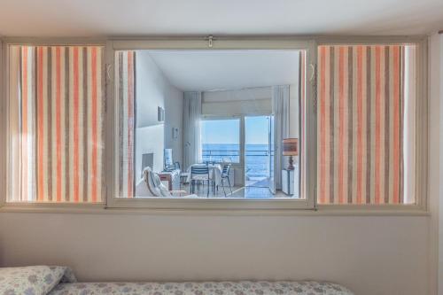 a bedroom with a large window and a dining room at La finestra sul mare in Ospedaletti