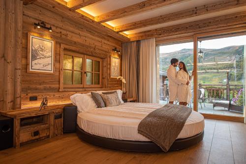 two people standing in a bedroom with a bed at Le Chalet Suite Livigno in Livigno