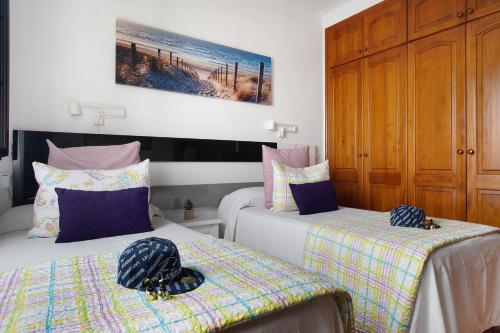 a bedroom with two beds and a wooden cabinet at Casa Lancelot in Tinajo