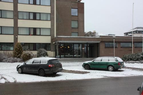 two cars parked in a parking lot in front of a building at Hotel Madona in Madona