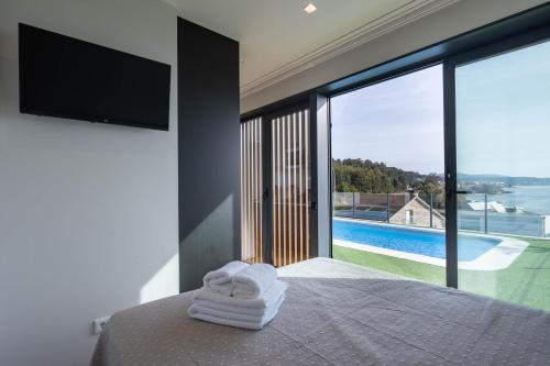 a bedroom with a bed with a view of a pool at Complejo Bungalow con piscina in A Pobra do Caramiñal