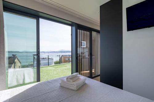 a bedroom with a bed with a view of the ocean at Complejo Bungalow con piscina in A Pobra do Caramiñal