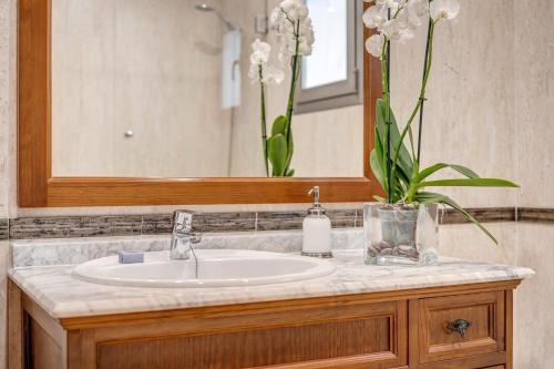 a bathroom sink with a mirror and a vase of flowers at Villa Pintor in Port de Pollensa