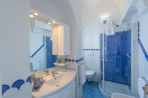a blue and white bathroom with a sink and a shower at Luxury Villa Soleluna con jacuzzi in Praiano