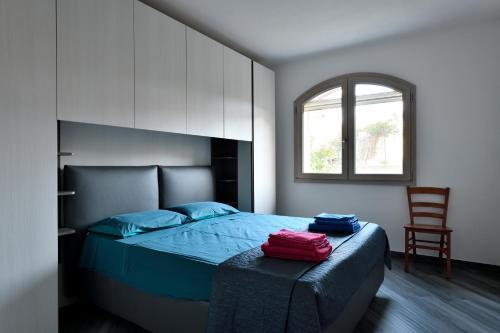 a bedroom with a bed and a chair and a window at Appartamento Latorre in Bari Sardo
