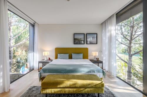 a bedroom with a large bed and large windows at Tróia Villa Paradise in Troia