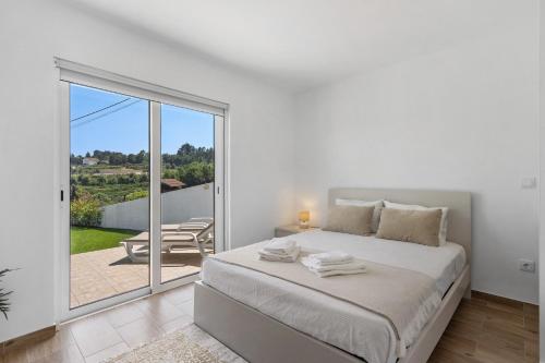 a white bedroom with a bed and a balcony at Refugio Das Vinhas in Celorico de Basto
