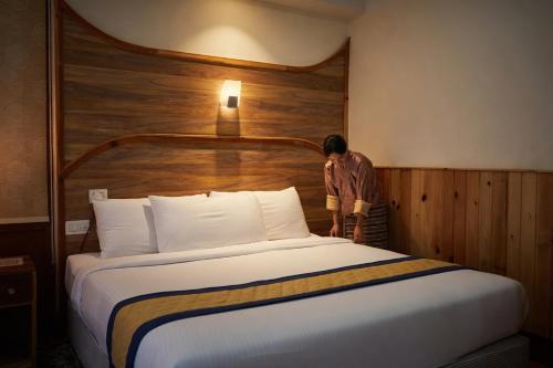 a person standing next to a bed in a hotel room at Norbu Lingka Resort in Tongsa