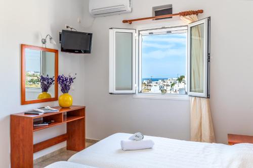 a bedroom with a bed and a window at Anemologio 303 Tinos in Agios Ioannis