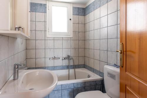 a bathroom with a tub and a sink and a toilet at Anemologio 303 Tinos in Agios Ioannis