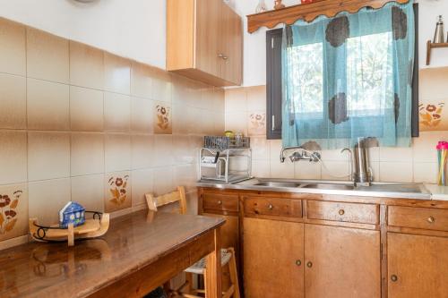 a kitchen with wooden cabinets and a sink and a window at Andros Traditional House in Andros