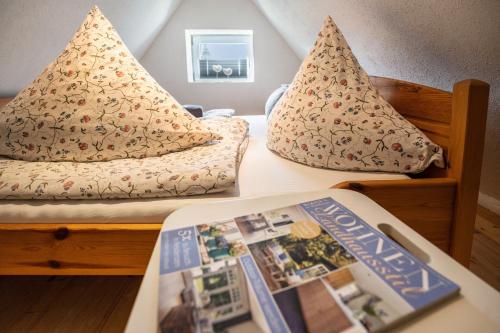 a bedroom with two beds with pillows and a book at Bezauberndes Lütt Hus in Damlos