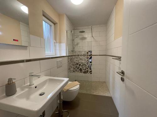 a white bathroom with a sink and a toilet at Ferienhaus Eichelhäher in Zossen