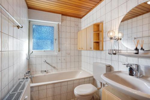 a bathroom with a tub and a toilet and a sink at Ferienwohnung Huckelberg in Schmallenberg