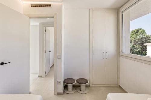 a bedroom with white walls and a window and two stools at Apartamento ático en L'Escala in L'Escala