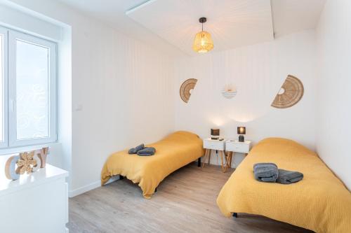 two beds in a white room with yellow sheets at La Goisette in Beauvoir-sur-Mer