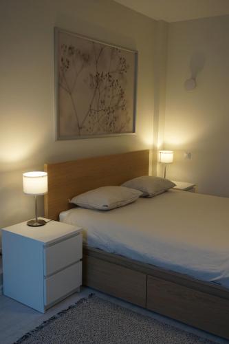 a bedroom with a bed with two lamps on it at Kaiju Apartment 15 in Liepāja