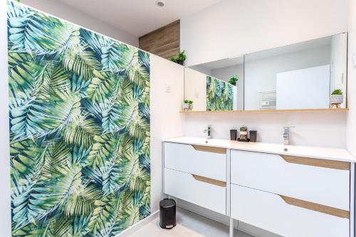 a bathroom with a tropical leaf wallpaper at La Goisette in Beauvoir-sur-Mer