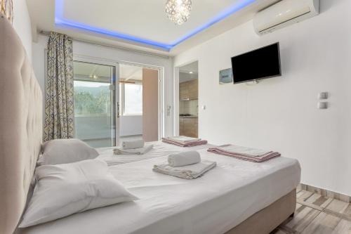 a large white bed in a room with a tv at Villa Dionysia Studio S2 in Alikanas