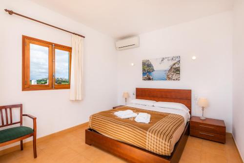 a bedroom with a bed and a chair and a window at Finca Goet in Sa Pobla