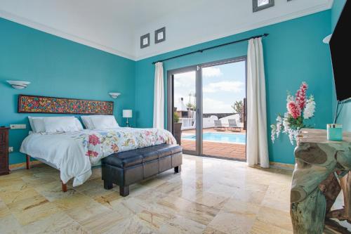 a bedroom with blue walls and a bed and a pool at Villa Capricho in Lanzarote