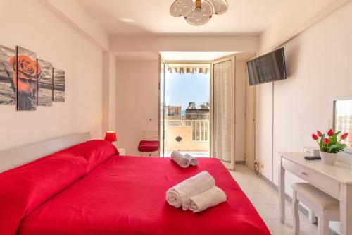 a red bed in a white room with a window at Casa Riviera in Donnalucata