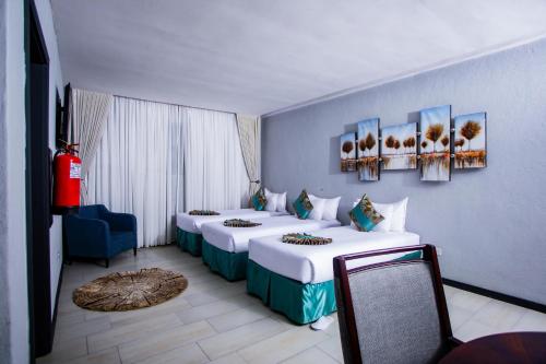 a room with three beds and a blue wall at Urban Bliss Hotel in Kabwe