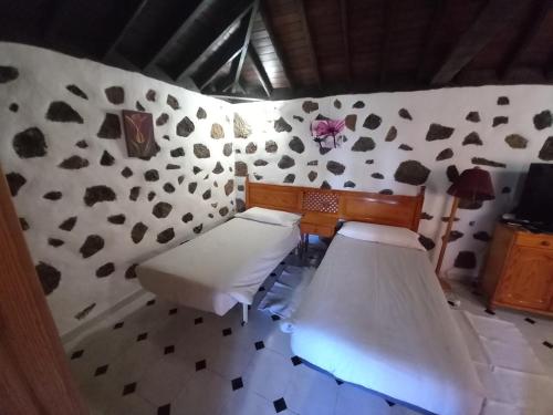 ein Zimmer mit zwei Betten in einem Zimmer mit einer Wand in der Unterkunft La Carpintera in Tijarafe