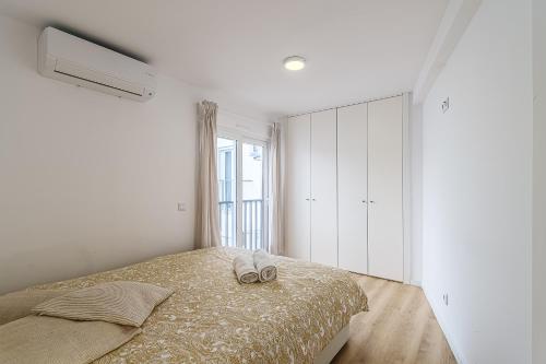 a white bedroom with a bed and a window at Beach House In Sesimbra in Sesimbra